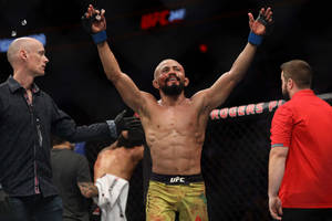 UFC拳手在八角籠內高舉雙臂慶祝勝利。 — 勝利 壁紙