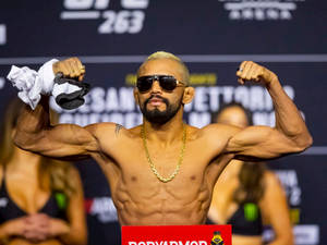 一位赤裸上身的MMA拳手在UFC稱重活動中彎曲手臂展示肌肉。