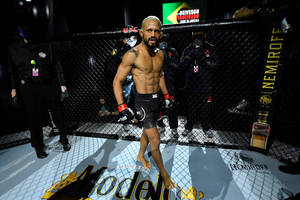 一位赤裸上身的MMA拳手在UFC八角籠中行走，贊助商標誌清晰可見。