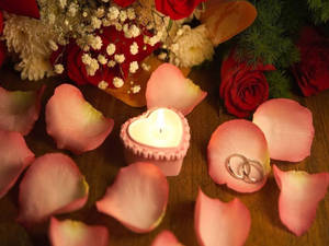 心形蠟燭被玫瑰花瓣和結婚戒指包圍在木頭上。 — 花 壁紙
