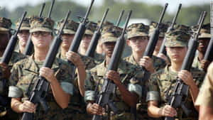 身穿制服的女海軍陸戰隊員在戶外以紀律嚴明的隊形持步槍。