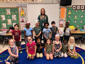 一位老師和她多元化的年輕學生班級在充滿活力的課室中一起拍照。