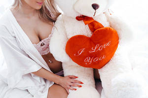 身穿白色浴袍的女子擁抱泰迪熊，泰迪熊拿著寫有I Love You的心形枕頭。 — 泰迪熊 壁紙