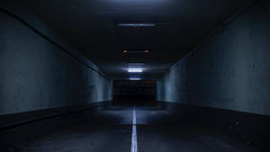 地下停車場中長而黑暗的混凝土隧道，帶有白色中線和閃爍的燈光。 — 最黑暗地牢 壁紙