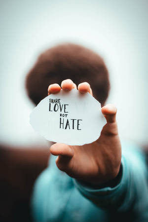 手拿著一張寫有share love not hate的紙。 — 語錄 壁紙