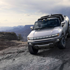 銀色Hummer EV SUV停放在岩石峽谷地形上，背景有層疊的平頂山。