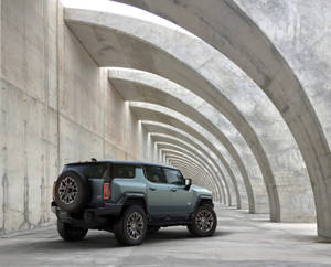 一輛綠色的Hummer EV SUV停放在混凝土拱門隧道下。 — 汽車 壁紙