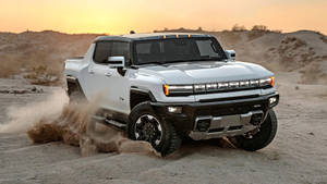 白色Hummer EV pickup truck在日落時分駛過沙漠沙地。