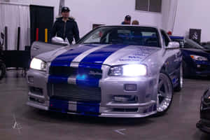 銀色和藍色的日產Skyline R34，帶有賽車條紋，在車展上展出。