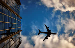 飛機飛過現代玻璃建築，天空中有雲。