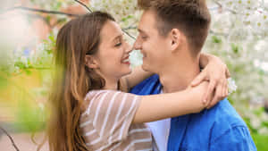 年輕情侶在櫻花樹下微笑擁抱。