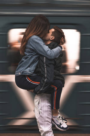 一名男子在行駛中的火車前抱起一名女子並親吻她。