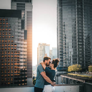 情侶在天台上接吻，背景是夕陽下的城市天際線