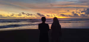 沙灘上情侶剪影觀賞海上多彩夕陽
