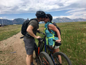 一對情侶與山地自行車站在小徑上接吻。