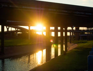 高速公路天橋後的夕陽，河流反射金色光芒