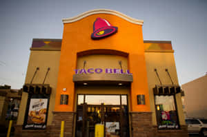黃昏時分的Taco Bell餐廳外觀，設有發光招牌和得來速窗口。