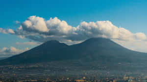 兩座火山聳立於城市之上，天空湛藍，白雲朵朵。