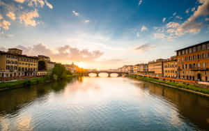 夕陽映照河流，河上有石橋，兩岸有歷史建築。