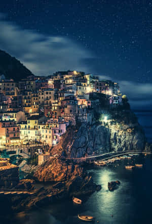 星空下，港灣中有船隻的夜間懸崖村莊。