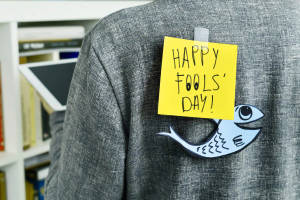 一張黃色便利貼寫著「HAPPY FOOLS' DAY!」，貼在灰色外套上，並有一個紙魚。