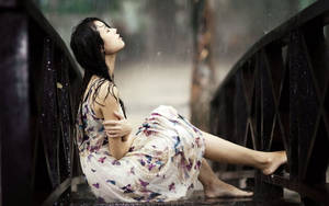 穿蝴蝶裙女子雨中坐在濕橋欄杆上