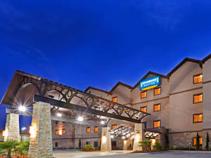 暮色中的 Staybridge Suites 酒店，窗戶明亮，石拱門。