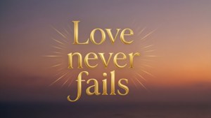 金色發光文字 'Love never fails' 喺日落天空上。