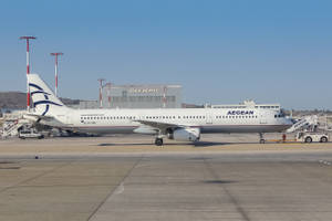 愛琴海航空飛機停在機場閘口，背景有奧林匹克建築。
