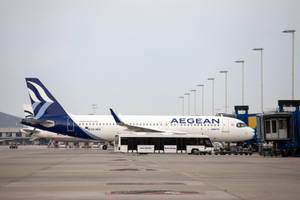 愛琴海航空飛機停泊在機場閘口，附近有穿梭巴士。