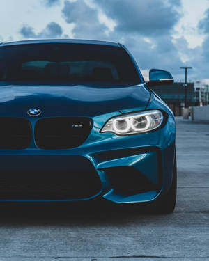藍色BMW M2跑車，車頭燈亮起，停泊喺戶外。 — 汽車 壁紙