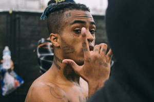 有紋身、藍色辮子頭的男人做手勢。