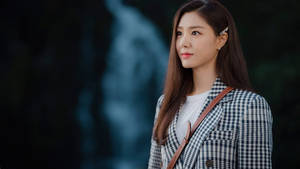 身穿格仔西裝外套的女性在黃昏時分站在瀑布附近
