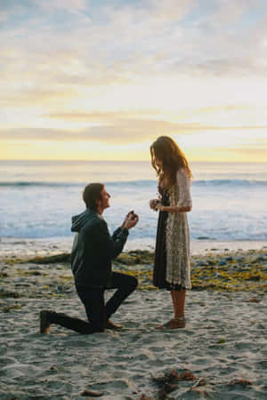 男子在日落沙灘上向女子求婚，身後有海浪