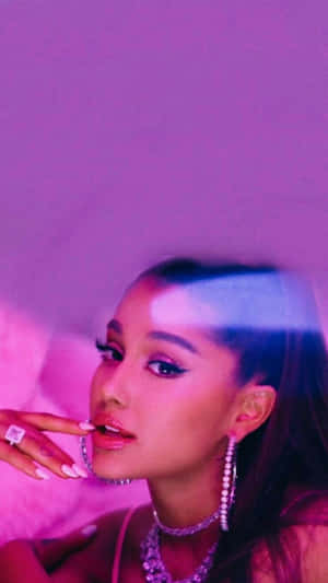 Ariana Grande 在紫色燈光的房間中，佩戴閃閃發光的珠寶和鑽石戒指。