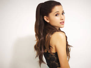 Ariana Grande 身穿黑色蕾絲上衣，高馬尾，越過肩膀看。