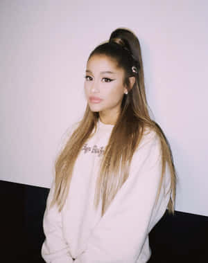 Ariana Grande 身穿白色衛衣，頭髮紮成高馬尾。