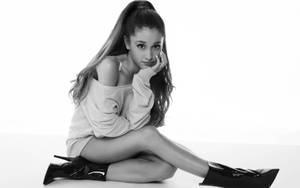 Ariana Grande 坐在黑白工作室中，穿著靴子和毛衣。