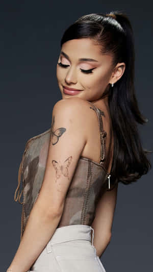 Ariana Grande 在工作室肖像中手臂上有蝴蝶紋身。
