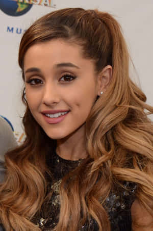 Ariana Grande 在活動中微笑，長長的波浪髮紮成高馬尾。