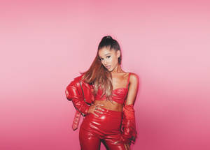 Ariana Grande 穿著紅色皮革套裝在粉色背景前