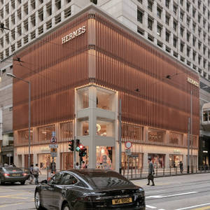 Hermes 奢侈品店位於街角，有發光窗戶和經過的汽車。