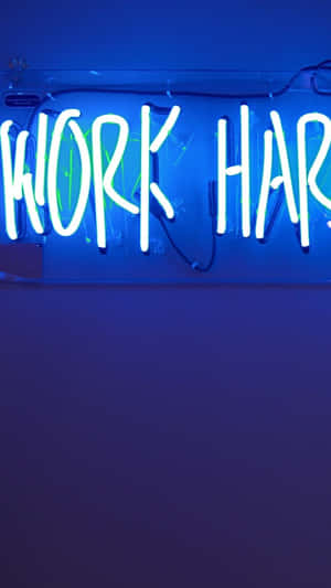 霓虹燈牌寫著 work hard 喺藍色牆上，有可見嘅電線。 — 霓虹 iPhone 壁紙