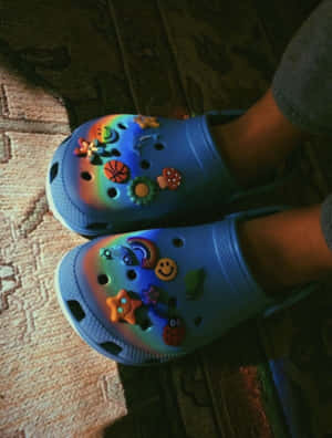 藍色Crocs鞋配彩色吊飾，置於圖案地毯上室內。