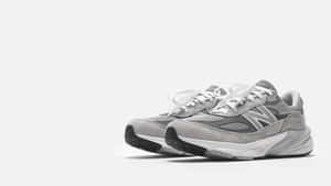 純白色背景上的灰色 New Balance 運動鞋，配有白色鞋帶和厚鞋底。
