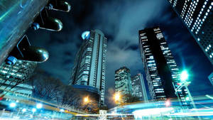 夜間城市景觀，燈火通明的摩天大樓和移動車輛的光軌。
