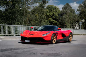紅色法拉利 LaFerrari 配金色輪胎，停泊在樹旁的道路上。