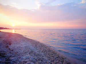 平靜海洋上的夕陽，前景是沙灘