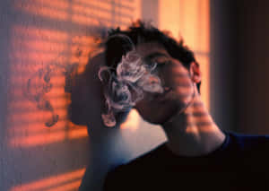 一個人在溫暖的橙色光線中呼出煙霧，牆上有條紋陰影。