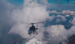 藍色直升機在積雪山峰附近的雲層上方飛行